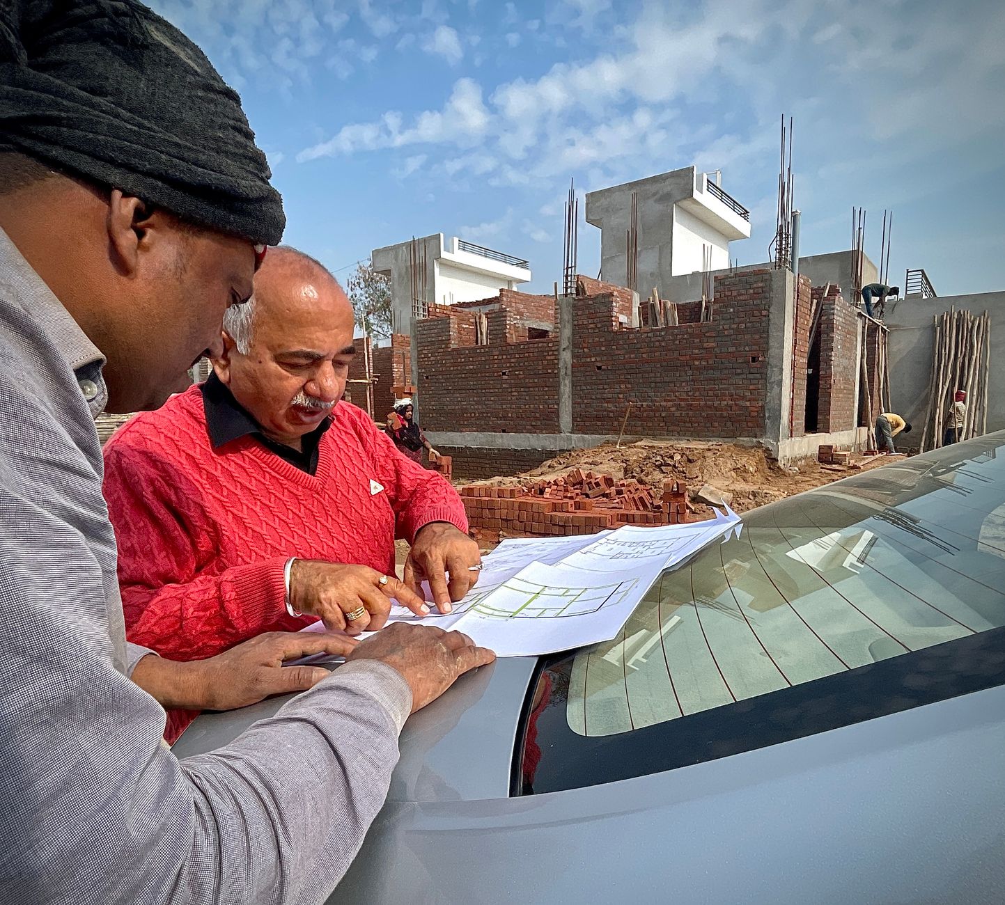 men standing and looking at paper on car