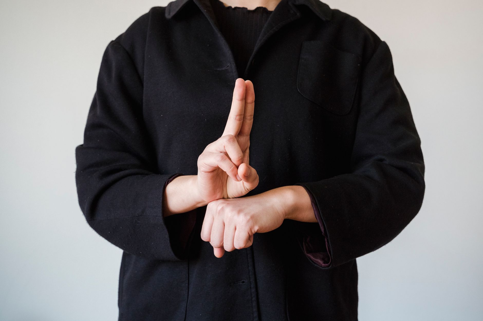 man in a black coat showing a sign in a sign language